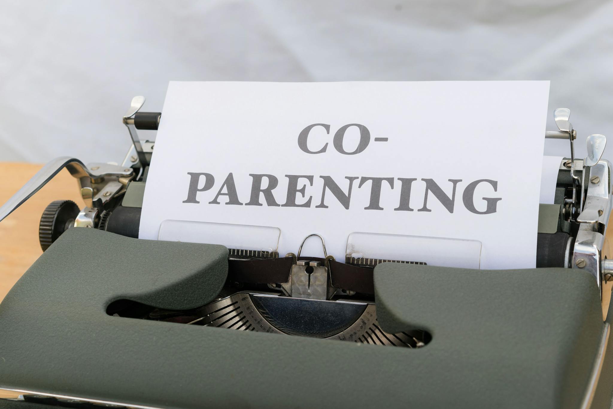 Pricing A vintage typewriter displaying a paper with the word 'Co-Parenting', symbolizing shared parenting or custody.