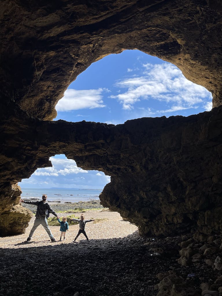 Home Father with children in a UK seaside cave, perfect for adventure-themed imagery.